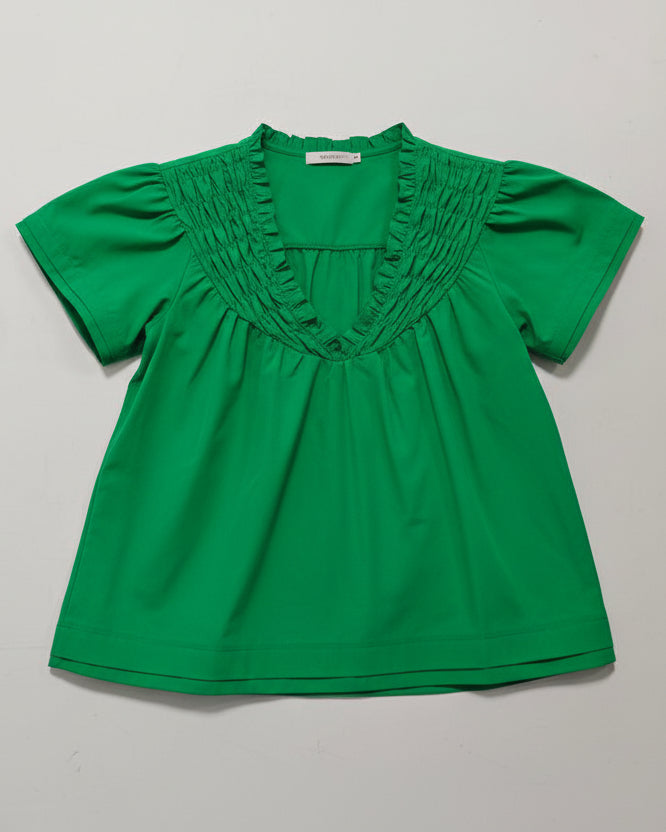 Green blouse on a mannequin against a gray background